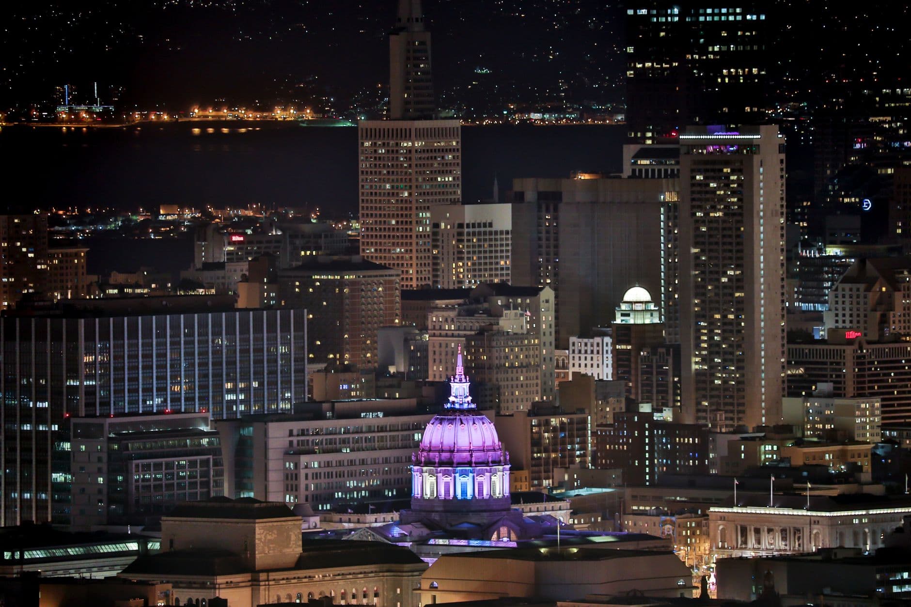 A stunning view of San Francisco skyline at night, featuring a brightly lit dome.